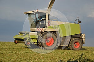 Combine harvester mows the field, harvester unloading into a tractor trailer