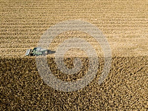 Combine harvester picking seed from fields, aerial view of a field with a combine harvester with cornhusker gathering the crop