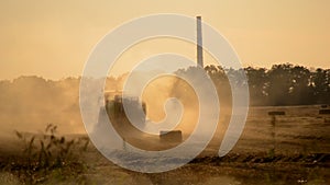 Combine harvester pressing straw field bales driving across field sunny summer