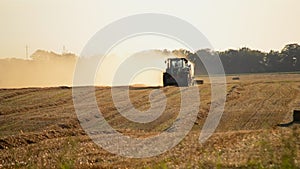 Combine harvester pressing straw field bales driving across field sunny summer