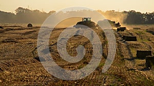 Combine harvester pressing straw field bales driving across field sunny summer