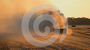 Combine harvester pressing straw field bales driving across field sunny summer