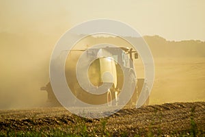 Combine harvester pressing straw field bales driving field sunny summer evening