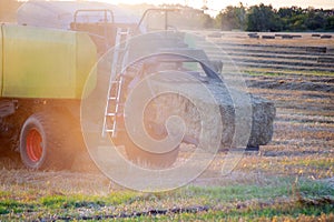 Combine harvester pressing straw field bales driving field sunny summer evening