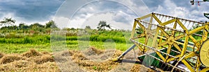 Combine harvester reel. Combine getters grain crop on the agricultural field. Weather with gloomy sky threatens the harvesting.