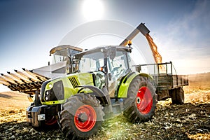 Combine harvester and tractor with trailer unloading harvest. Farmer working details. Agriculture industry machinery.