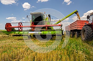 Combine harvester unloads wheat into the tractor