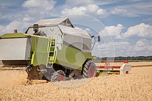 Combine harvester on a wheat field with a cloudy sky