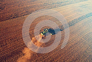 Combine harvester working on harvesting rapeseed, aerial view. Farm Harvest season in rural. Harvester for agriculture work.