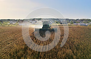 Combine harvester working on harvesting rapeseed, aerial view. Farm Harvest season in rural. Harvester for agriculture work.