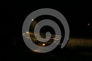 Combine harvester working in a wheat field at night with lights