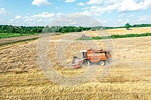 Combine harvester working on a wheat field. summer landscape under blue sky with clouds. aerial photo