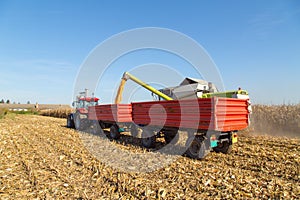 Combine harvesting corn and unloading grains in to tractor trailer