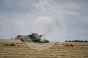 The combine harvests the ripe golden wheat in the grain field. Agricultural work in summer. Ãšri, Hungary - 22/07/2020