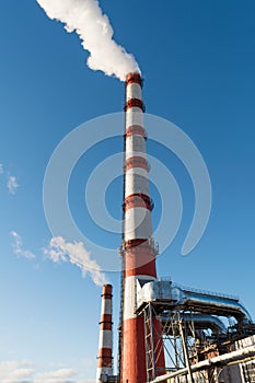 Combined heat and power plant, from the pipe goes white smoke against a background of pure blue sky