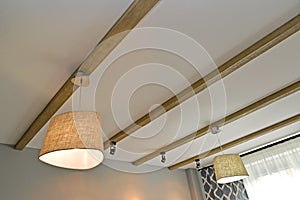 The combined lighting - ceiling chandeliers and laid on lamps on the wooden beams fixed on a ceiling