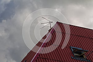 Combined TV antenna mounted on the red roof of the building. TV antenna meter and decimeter.