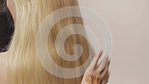 Combing hair on blond with long hair. Closeup