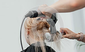 Combing the hair drying brush. Stylist drying woman hair in hairdresser salon photo