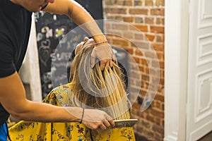 Combing hair. Professional hairdresser using a comb on his client& x27;s blond hair. Expert hair-salon concept.