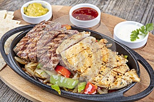 Combo Fajita; top down photo of mexican steak and chicken fajitas in iron skillet with corn tortillas