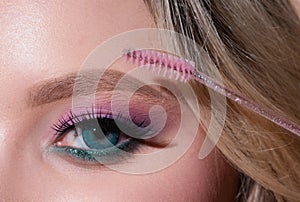 Combs eyebrows with a brush in a beauty salon. Woman with long eyelashes and thick eyebrows. Macro close up of brows.