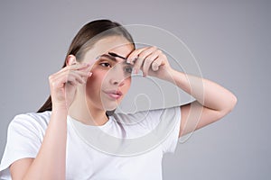 Combs eyebrows with a brush in a beauty salon. Woman with long eyelashes and thick eyebrows. Natural beauty brows. Young