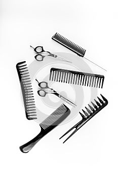 Combs, hairbrush, scissors - hairdresser eqiupment - on white table top-down