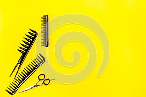 Combs, hairbrush, scissors - hairdresser eqiupment - on yellow table top-down space for text