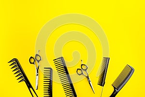 Combs, hairbrush, scissors - hairdresser eqiupment - on yellow table top-down space for text