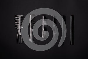 Combs and hairdresser tools on black background top view