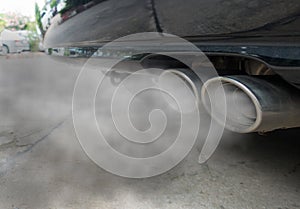 Combustion fumes coming out of black car exhaust pipe, air pollution concept photo