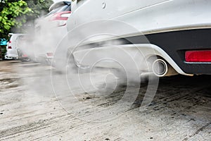 Combustion fumes coming out of white car exhaust pipe, air pollution concept