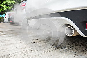 Combustion fumes coming out of white car exhaust pipe, air pollution concept