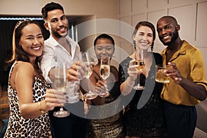 Come celebrate with us. Shot of a diverse group of friends standing together and holding glasses of champagne during a
