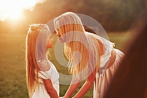 Come on, give me a kiss. Mother and daughter enjoying weekend together by walking outdoors in the field. Beautiful nature
