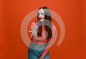 Come here, follow me. Modern young girl calling with hand, making beckoning gesture, inviting on orange background