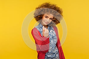 Come here, follow me! Portrait of pretty curly-haired woman looking playfully and calling with one finger