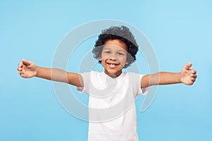 Prísť voľný! portrét pôvabný malý chlapec kučeravý vlasy držanie ruky široký otvoriť na objatie 