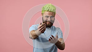 Come here. Positive bearded man with dyed green hair calling you with finger
