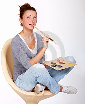 Come on imagination...a thoughtful-looking young woman sitting in chair holding a paintbrush and palette.