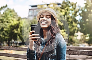 Come join me on this beautiful day. an attractive young woman using a cellphone at the park.