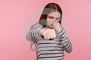 Come on, let`s fight! Portrait of aggressive angry woman in striped sweatshirt boxing to camera, punching