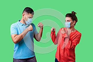 Come on let`s fight! Portrait of couple with surgical medical mask standing together, keeping fists clenched and looking at each
