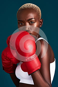 Come at me. Cropped portrait of an attractive young female boxer working out against a dark background in the studio.