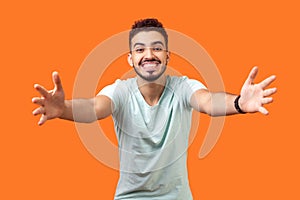 Come into my arms. Portrait of good natured, extremely happy brunette man stretching arms to hug you. indoor studio shot isolated