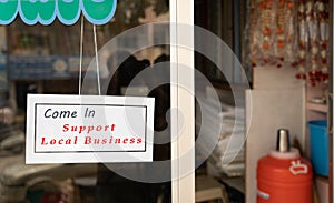 Come in support local business signage attached infront of door during coronavirus or covid-19 pandemic to support local