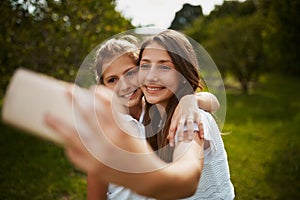 Come take a selfie with me. two young sisters taking selfies in the park.