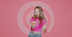 Come to me. Funny playful child girl inviting to approach, making beckoning gesture on pink studio background