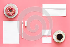 Come up with brand identity. Blank stationery for branding near coffee and donut on pink background top view mockup